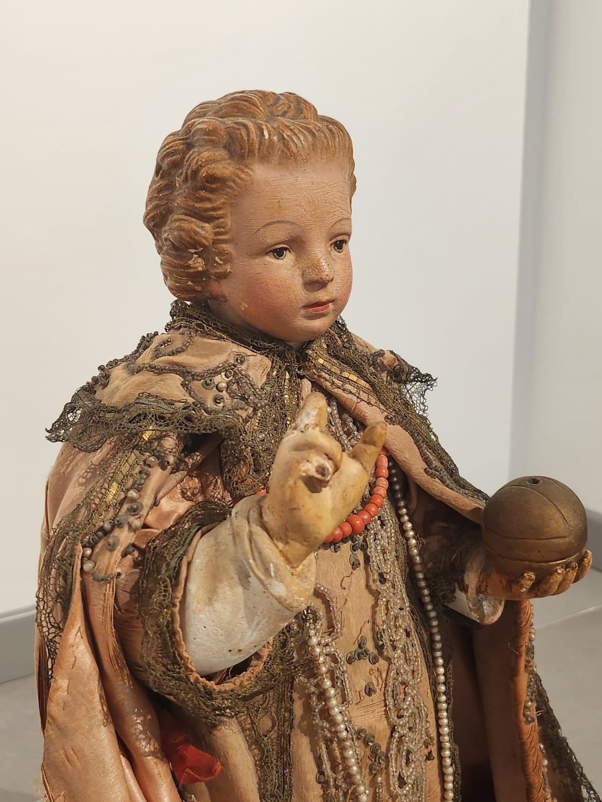 Bambinello in terracotta con vesti con intarsi e collana in corallo